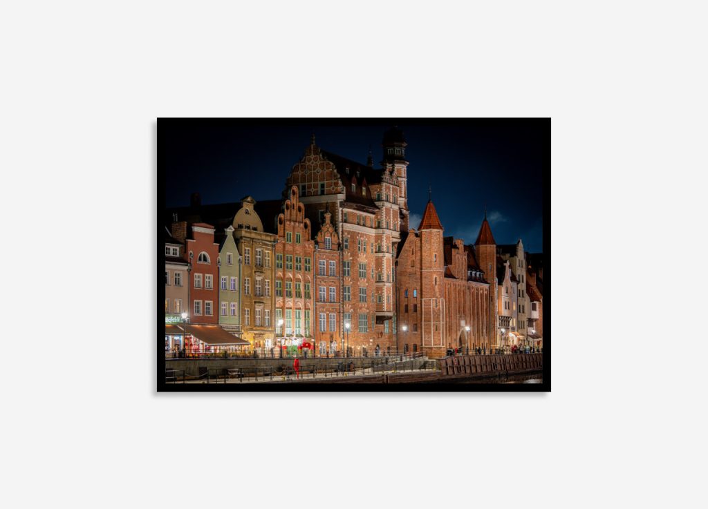 Gdansk buildings glowing at night with historic Gothic and Renaissance architecture, city lights, and reflections along the tranquil riverfront
