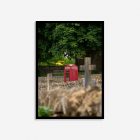 Traditional red phone booth beside a historic graveyard with a carved Christian cross, captured in a quaint English village in the Cotswolds.